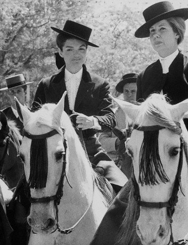 23 Apr 1966, Seville, Spain --- Jacqueline Kennedy rides a horse beside another woman at the spring fair in Seville. The two wear typical Andalusian riding outfits. --- Image by © Bettmann/CORBIS